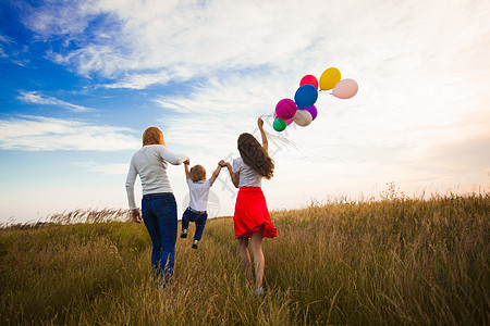 两个女孩个小男孩带着气球田野里跑步妈妈她的孩子家人田野上散步图片