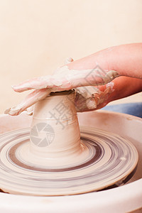 女孩的手谁试图用白色粘土陶工的车轮上陶器图片