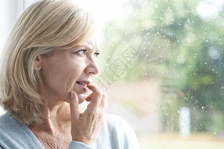下雨窗边悲伤成熟的女人患广场惧症,望着窗外背景