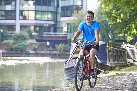 轻人城市环境中骑自行车河边图片