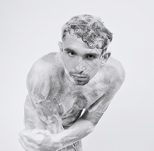 轻的男子泡沫中洗澡,白色背景上个美丽的身体图片