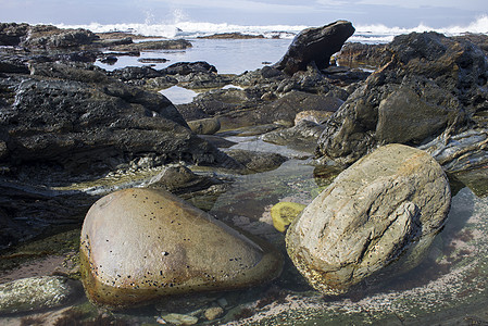 两块大巨石躺崎岖海岸线上的岩石池里图片