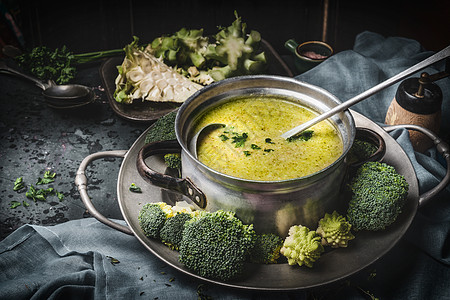 烹饪锅与绿色罗曼斯科西兰花汤勺子黑暗的乡村厨房桌子上健康食品饮食营养理念图片