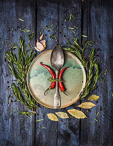 芳香的草药香料与勺子盘子,深蓝色的木制背景,顶部的视图图片