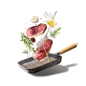 飞生牛肉牛排,香草,油香料与烤盘厨房用具,隔离白色背景,正视图飞行食物的背景图片