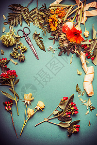 花艺桌上的秋花,蓝色背景上的丝带剪刀,顶部的景色,框架秋天的花准备图片