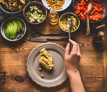 健康素食沙拉吧女用勺子把食物放盘子上,俯视清洁饮食饮食食物的图片