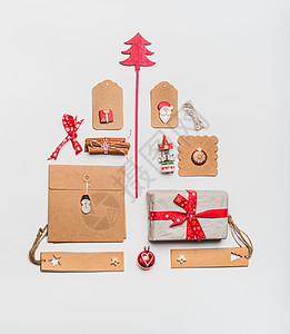 诞树布局与工艺纸包装礼品盒,标签,玩具,红色节日装饰香料白色书桌背景,顶部视图,平躺贺卡的节日图案图片