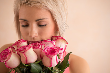 轻漂亮的女人着粉红色的玫瑰她很满意情人节国际妇女节庆祝活动图片