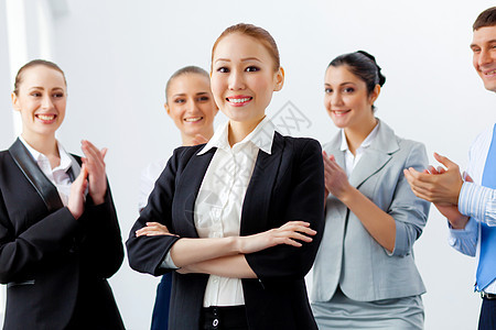 亚洲商界女与同事轻的亚洲女商人与同事微笑,后台高兴地鼓掌图片