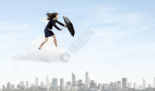 商务雨伞商业上的挑战轻坚定的女商人逆着强风行走背景