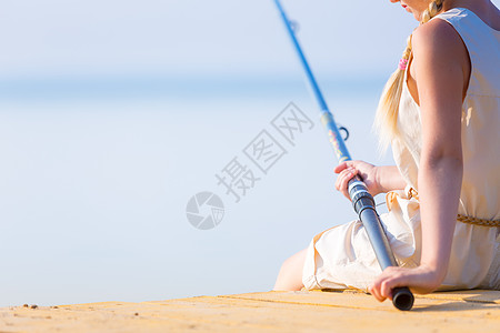 穿着连衣裙帽子的女孩带着钓鱼竿码头钓鱼图片