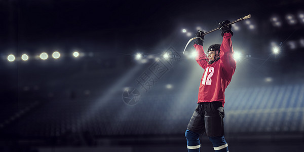 冰球运动员冰上穿着红色制服的曲棍球运动员聚光灯下的冰场上图片