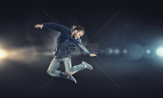 跳舞现代风格的男舞者聚光灯下跳跃图片