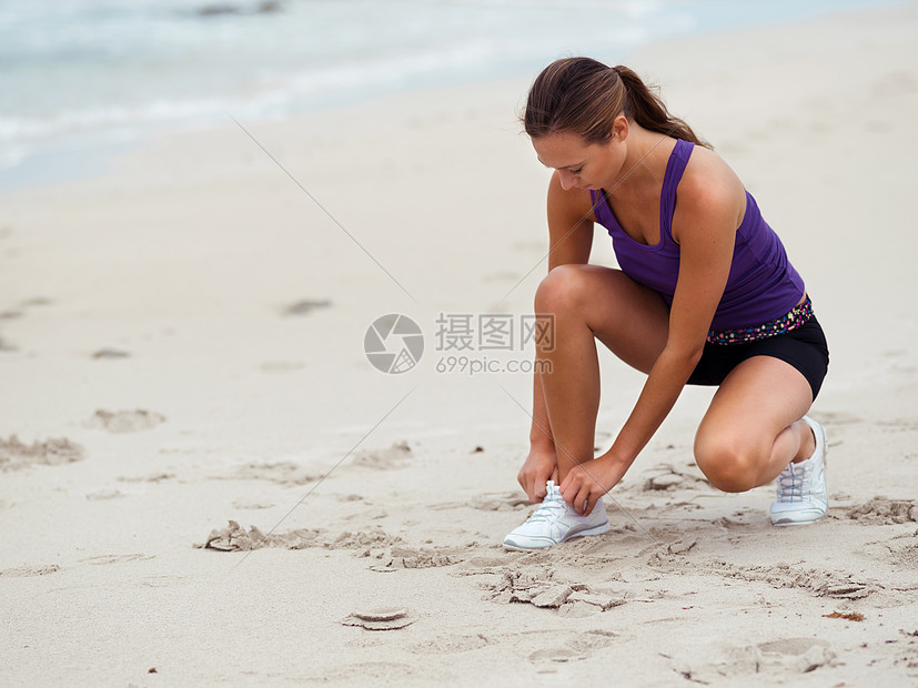 运动的轻女人海边她的鞋带图片