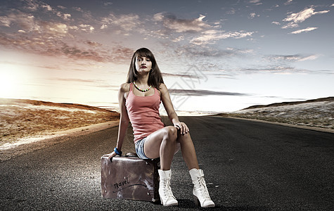 自动启动旅行轻漂亮的女孩旅行者坐路边的手提箱上图片