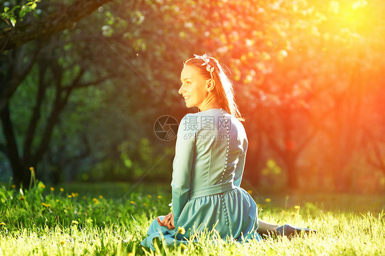 苹果花中位穿着连衣裙的漂亮女人的户外肖像图片