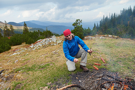 徒步旅行的人山上的篝火上准备美味的香肠图片