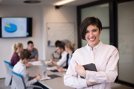 轻的西牙裔女商人肖像与平板电脑现代创业公司办公室内部,人们队会议上的背景图片
