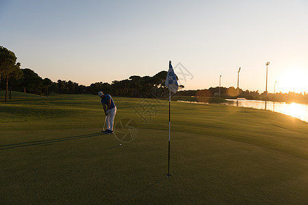 高尔夫球手与司机美丽的日落球场击球图片