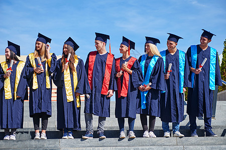 毕业日,轻的毕业生们站大学大楼前图片