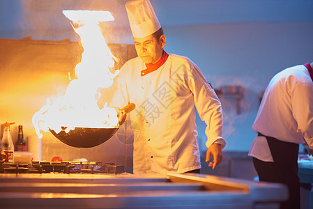 酒店厨房的厨师用火准备蔬菜食品图片