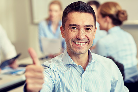 商业,人队合作的微笑的商人表现出竖大拇指与群商人办公室开会图片