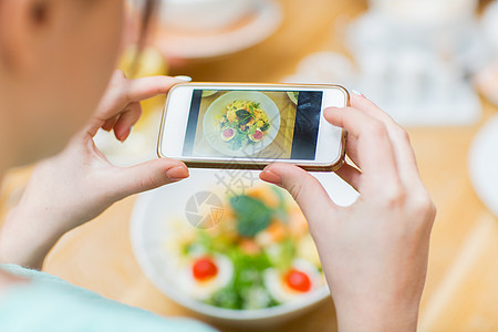 人,休闲技术的近距离的女人手与智能手机拍照的食物餐厅背景