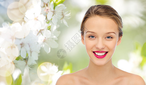 美丽,人与健康的微笑的轻女人的脸与粉红色口红嘴唇肩膀上夏季绿色自然背景与樱花图片