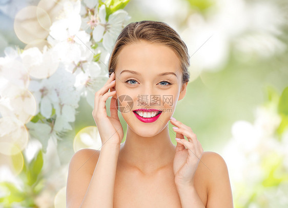美丽,人与健康的微笑的轻女人的脸与粉红色的口红嘴唇肩膀上绿色的自然背景与樱花图片