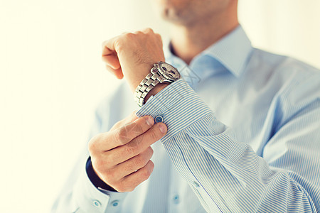 人,商业,时尚服装的男人紧固按钮衬衫袖子家里背景图片