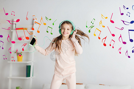 人们,孩子,睡衣派技术快乐的微笑女孩戴着耳机,用智能手机床上跳跃,家听音乐背景图片