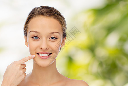 老年牙齿美丽,人,牙科护理卫生快乐的轻女人指着她的微笑牙齿绿色的自然背景背景