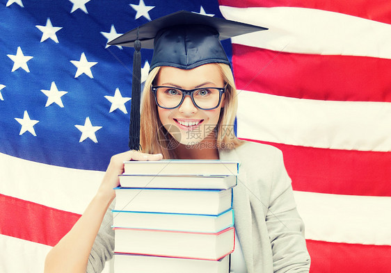 快乐的学生戴着毕业帽,书堆美国上戴毕业帽的学生图片