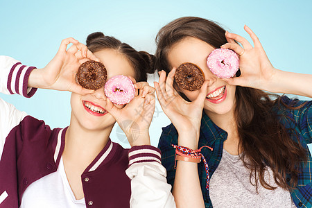 人,朋友,青少友谊的快乐的微笑,漂亮的十几岁的女孩与甜甜圈,脸,并蓝色背景图片