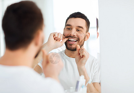 保健,牙科卫生,人美容微笑的轻人用牙线清洁牙齿,并家里的浴室照镜子图片