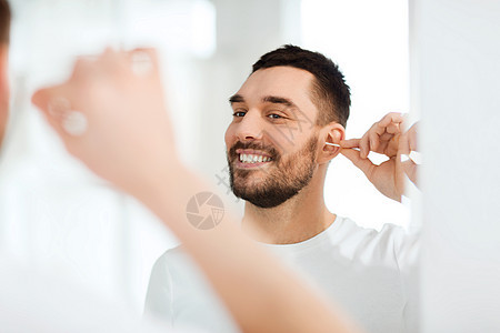 美丽,卫生人的微笑的轻人用棉签清洁耳朵,家里的浴室看镜子背景图片