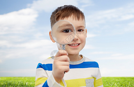 童,调查,发现,视觉人的快乐的小男孩透过放大镜看蓝天绿色的田野背景图片