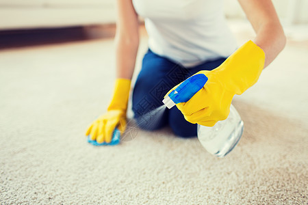 人,家务家务妇女戴橡胶手套与布喷雾清洁地毯家里图片