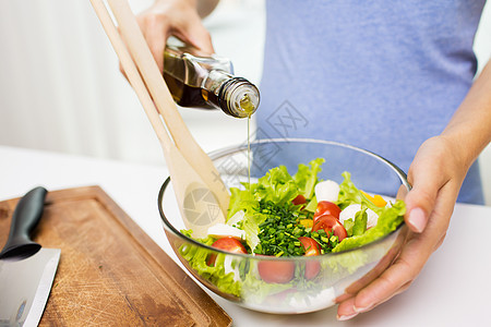 健康饮食,素食,饮食人们的密切轻妇女家里用橄榄油调味蔬菜沙拉背景图片