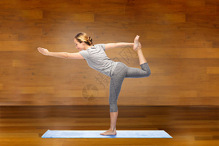 健身,运动,人健康的生活方式妇女瑜伽的主舞姿势垫子上的木制房间背景图片