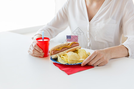 独立日,庆祝,主义节日的妇女吃热狗与美国装饰薯片,喝果汁庆祝7月4日家聚会图片