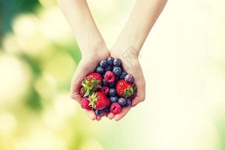 健康的饮食,节食,素食人们的靠近女人的手,着同成熟的夏季浆果绿色的自然背景下图片
