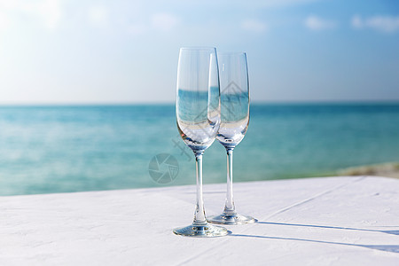 打开香槟饮料,假期,暑假庆祝两个香槟杯桌子上的海洋海滩背景