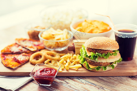 快餐健康的饮食汉堡芝士汉堡,油炸鱿鱼圈,炸薯条,饮料番茄酱木桌上背景图片