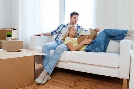 移动,人,维修房地产幸福的夫妇与大纸板箱沙发上的新家图片