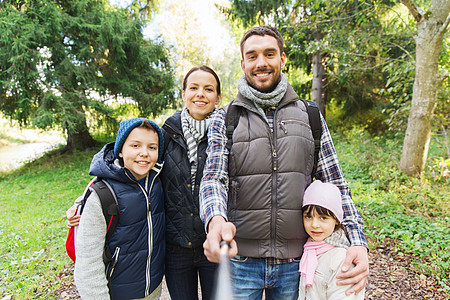 技术,旅游,徒步旅行人们的快乐的家庭与背包拍照自拍棒徒步旅行图片