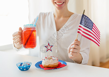 独立日,庆祝,主义节日的快乐的女人与甜甜圈庆祝7月4日,着美国,喝果汁璃梅森罐杯子家里背景图片