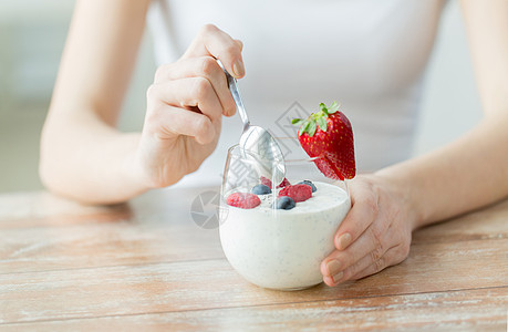 健康饮食,素食,饮食人的密切妇女的手与酸奶浆果桌子上图片