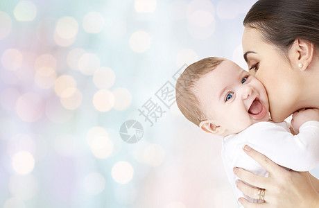 家庭,母亲,养育,人儿童保育的快乐的母亲亲吻可爱的婴儿蓝色假日灯光背景图片